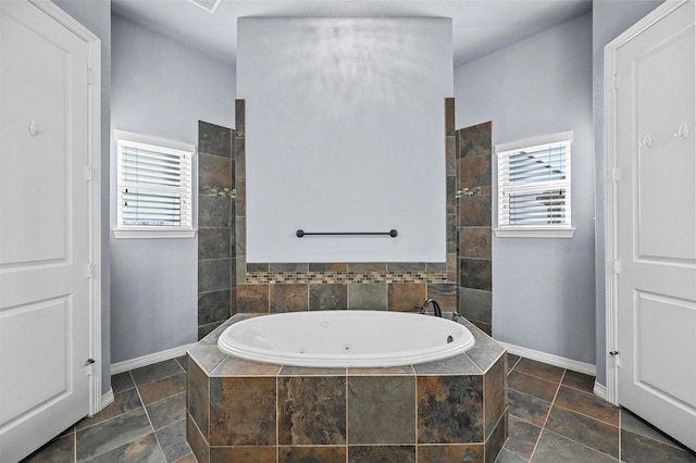 bathroom featuring plenty of natural light and a relaxing tiled tub