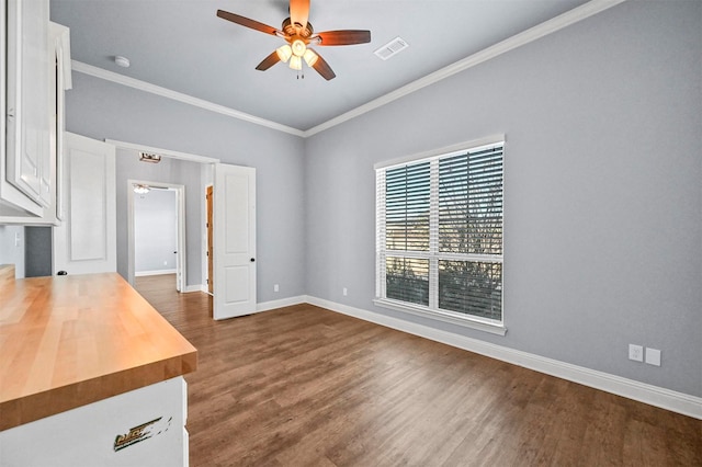 unfurnished room featuring ceiling fan, dark wood-type flooring, and ornamental molding