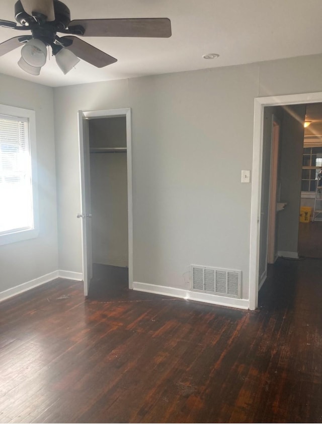 unfurnished bedroom featuring dark wood-type flooring, ceiling fan, and a closet