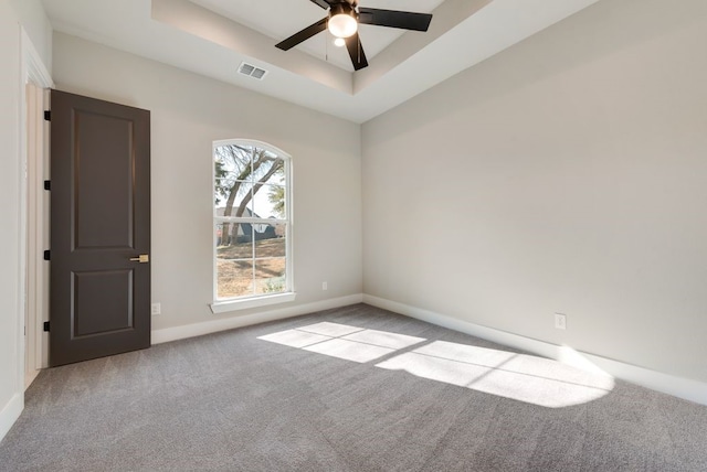 carpeted empty room with ceiling fan and a tray ceiling