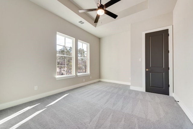 carpeted spare room featuring ceiling fan and a tray ceiling