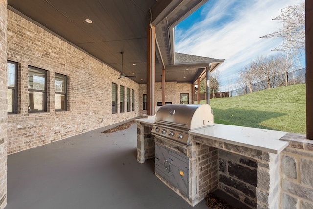 view of patio with exterior kitchen, area for grilling, and ceiling fan