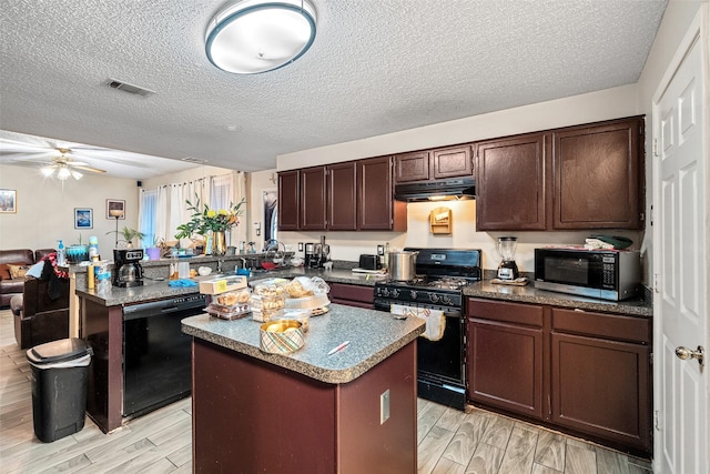 kitchen with a textured ceiling, black appliances, and a center island