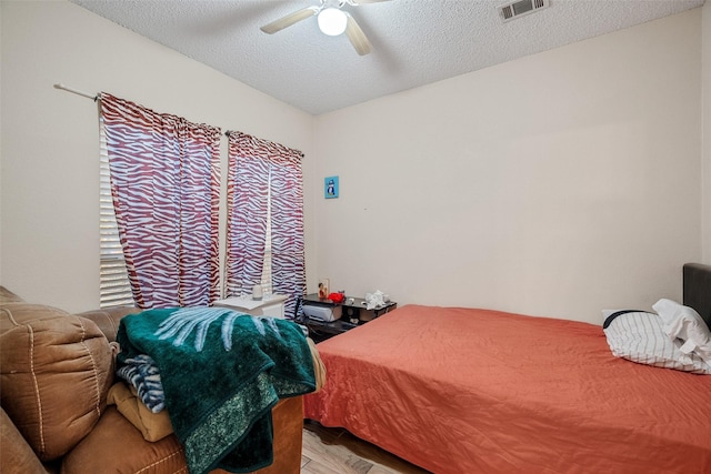 bedroom with a textured ceiling, light parquet floors, and ceiling fan