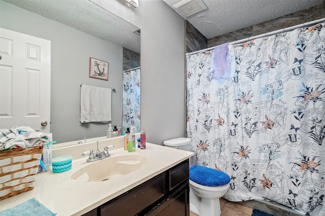 bathroom with toilet, walk in shower, tile patterned floors, vanity, and a textured ceiling