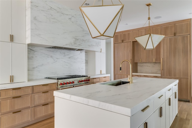 kitchen featuring sink, white cabinetry, decorative backsplash, double oven range, and a kitchen island with sink