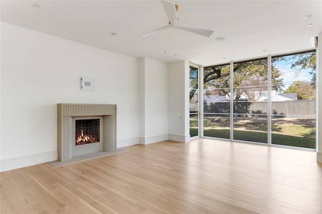 unfurnished living room with light hardwood / wood-style floors, ceiling fan, and expansive windows