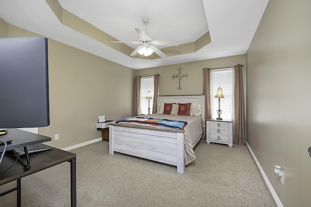 carpeted bedroom featuring ceiling fan and a tray ceiling