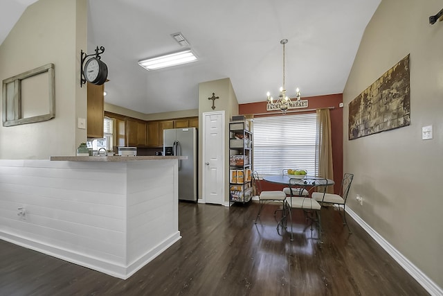 kitchen with stainless steel refrigerator with ice dispenser, dark hardwood / wood-style floors, plenty of natural light, and kitchen peninsula