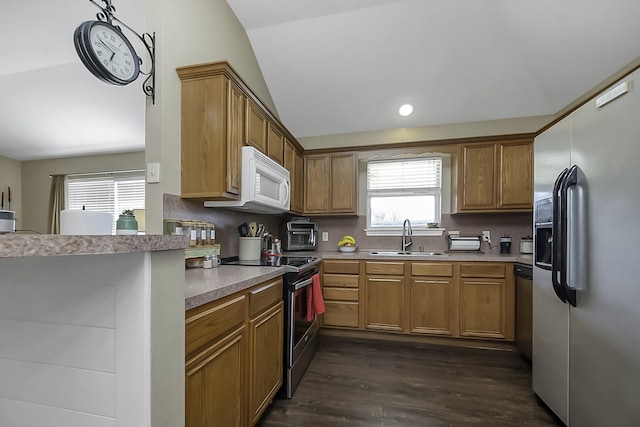 kitchen featuring vaulted ceiling, a wealth of natural light, stainless steel appliances, backsplash, and sink