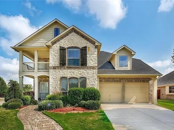 view of front of property featuring a balcony, a front lawn, and a garage