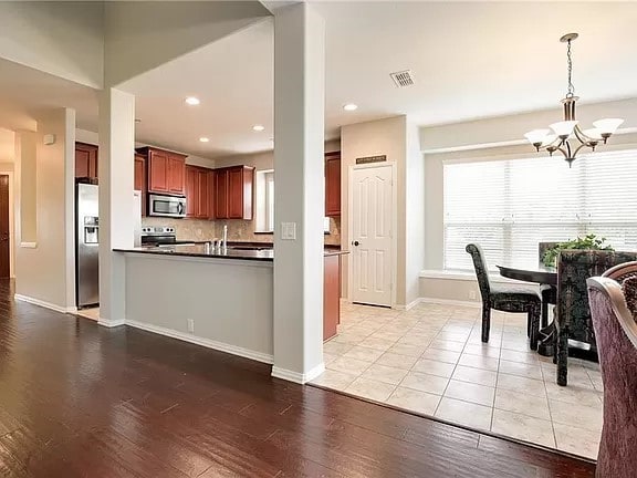 kitchen featuring stainless steel appliances, an inviting chandelier, kitchen peninsula, light hardwood / wood-style flooring, and hanging light fixtures