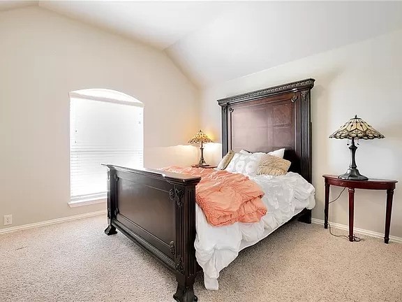 carpeted bedroom with lofted ceiling