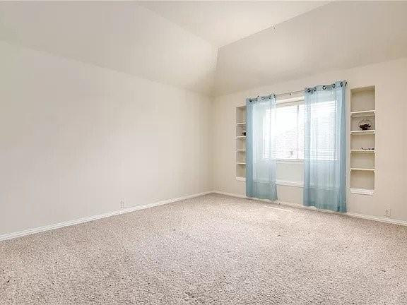 empty room featuring lofted ceiling and carpet