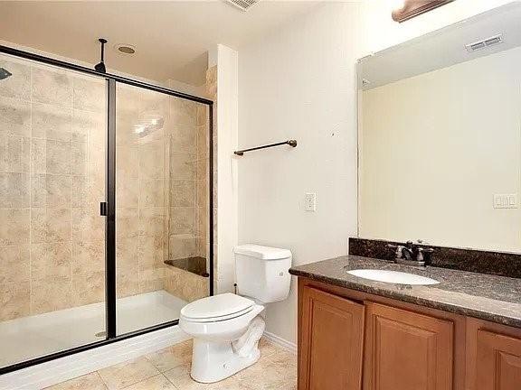 bathroom with tile patterned floors, an enclosed shower, vanity, and toilet