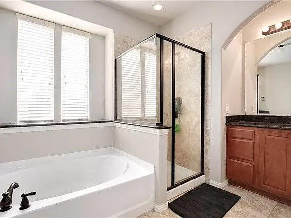 bathroom featuring vanity, plus walk in shower, and plenty of natural light