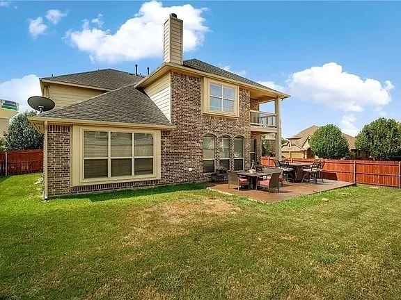 back of property with a lawn, a balcony, and a patio