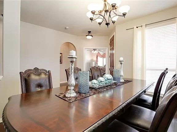 dining space featuring ceiling fan with notable chandelier