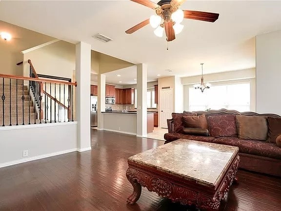 living room with dark hardwood / wood-style floors and ceiling fan with notable chandelier