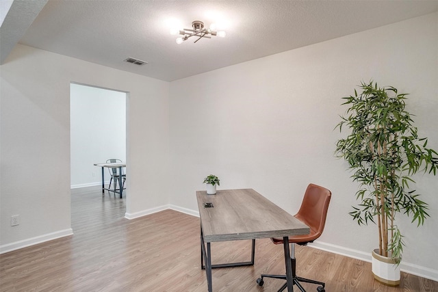 office space featuring an inviting chandelier, a textured ceiling, and hardwood / wood-style floors