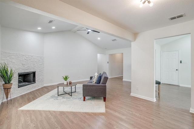 living area with a fireplace, ceiling fan, vaulted ceiling with beams, and light wood-type flooring