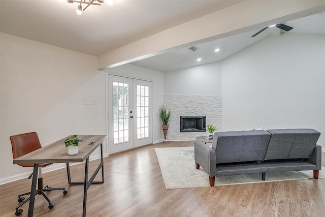 living room featuring a stone fireplace, light wood-type flooring, vaulted ceiling with beams, ceiling fan, and french doors