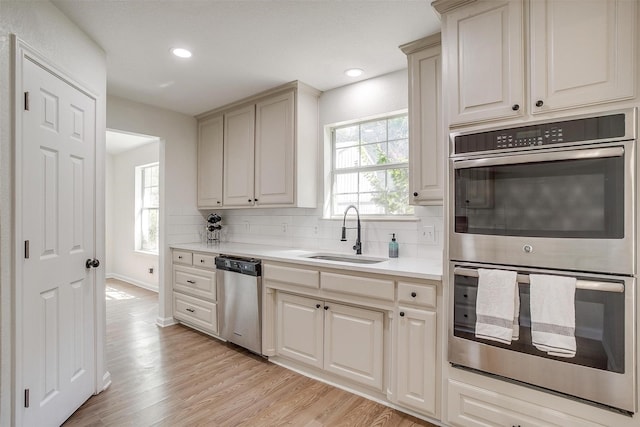 kitchen featuring stainless steel appliances, backsplash, sink, and light hardwood / wood-style floors