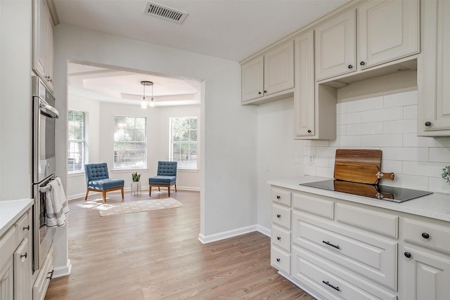 kitchen with a healthy amount of sunlight, pendant lighting, a raised ceiling, and tasteful backsplash