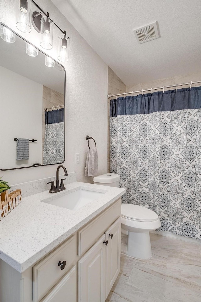 bathroom featuring toilet, a textured ceiling, and vanity