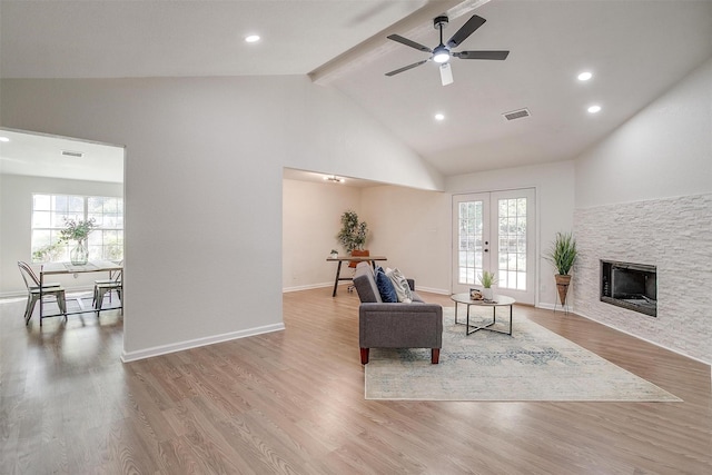 living room featuring a wealth of natural light, ceiling fan, light wood-type flooring, and vaulted ceiling with beams