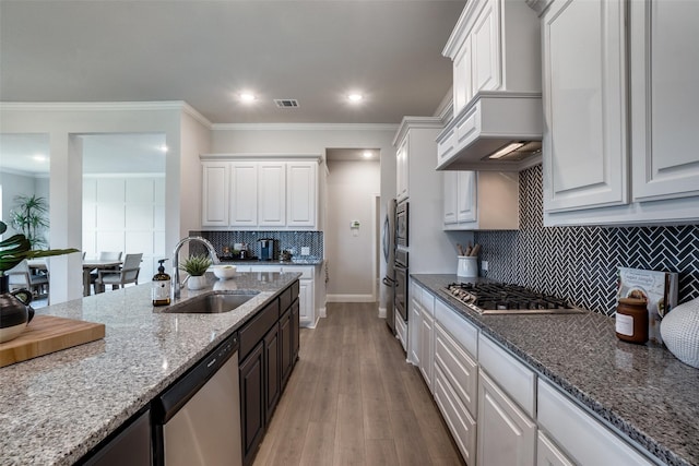 kitchen with light stone counters, light wood-type flooring, white cabinetry, appliances with stainless steel finishes, and sink