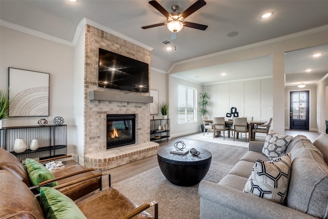 living room with ornamental molding, a brick fireplace, plenty of natural light, and wood-type flooring