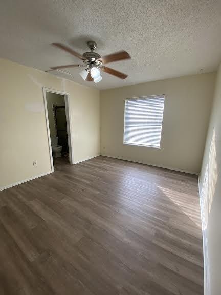 empty room featuring ceiling fan, baseboards, wood finished floors, and a textured ceiling