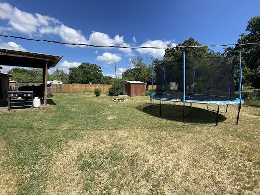 view of yard featuring a storage unit and a trampoline