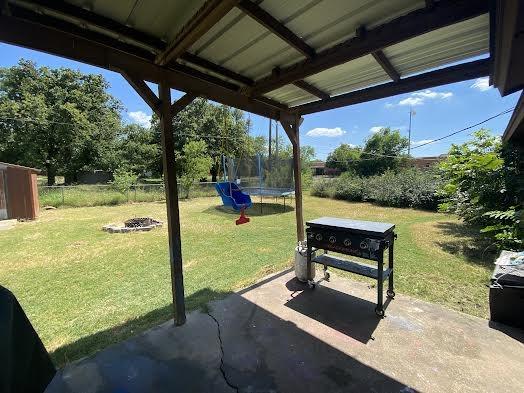 exterior space with a fire pit, a fenced backyard, and a trampoline