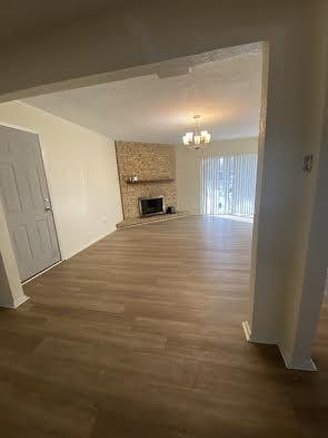 unfurnished living room with a fireplace, an inviting chandelier, and dark wood-type flooring