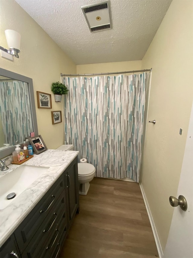 bathroom featuring toilet, vanity, a textured ceiling, and hardwood / wood-style floors