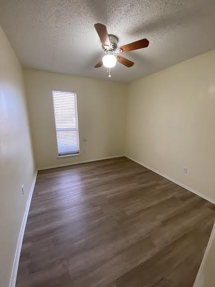 unfurnished room with a textured ceiling, dark wood-type flooring, and ceiling fan