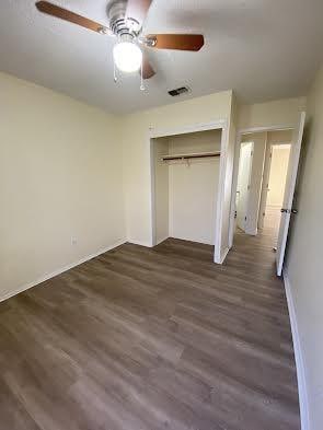 unfurnished bedroom featuring a closet, ceiling fan, and dark wood-type flooring