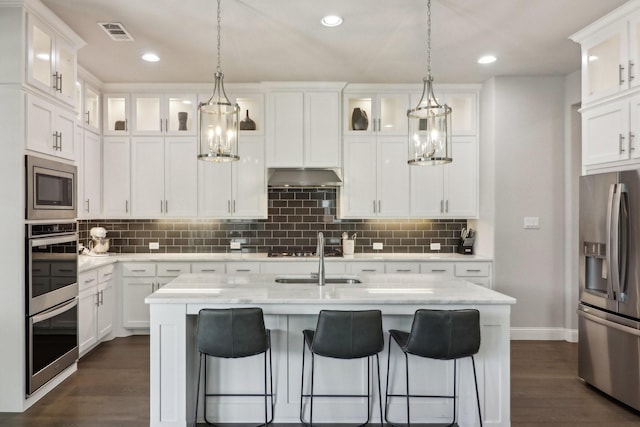 kitchen featuring visible vents, white cabinets, dark wood-type flooring, stainless steel appliances, and under cabinet range hood