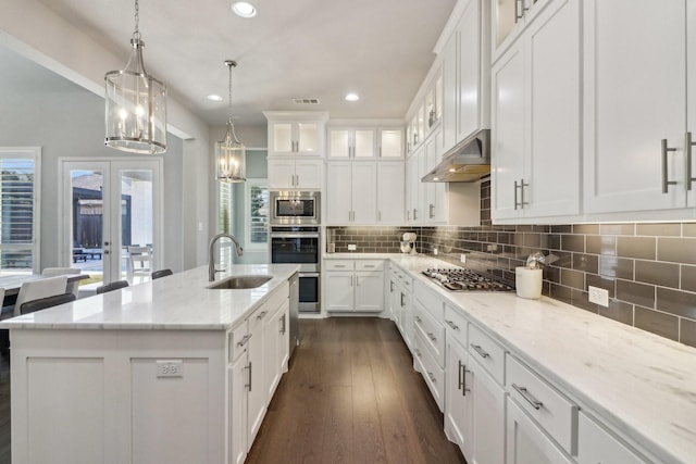 kitchen with french doors, a kitchen island with sink, white cabinets, appliances with stainless steel finishes, and sink