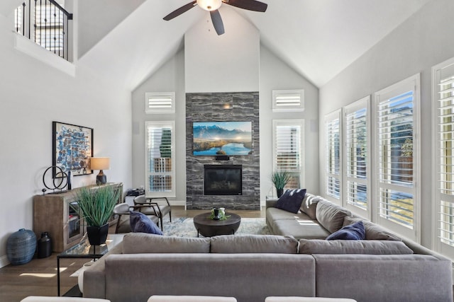 living area featuring ceiling fan, a premium fireplace, high vaulted ceiling, and wood finished floors