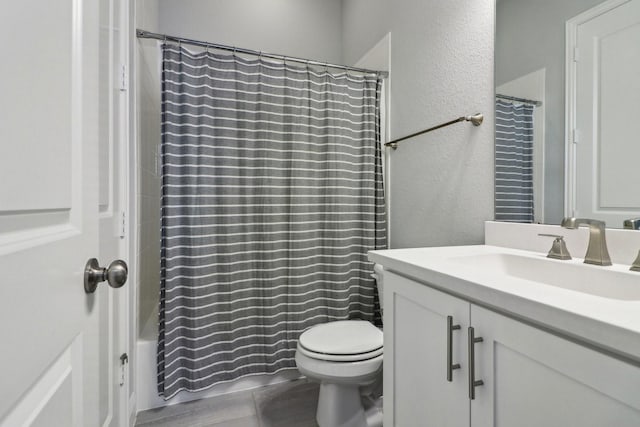 bathroom with shower / tub combo, a textured wall, vanity, and toilet