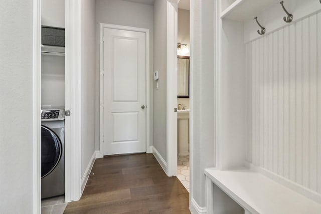 laundry area with dark wood-type flooring, washer / clothes dryer, baseboards, and laundry area