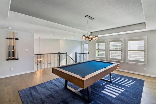 playroom with baseboards, hardwood / wood-style flooring, a tray ceiling, a textured ceiling, and a chandelier