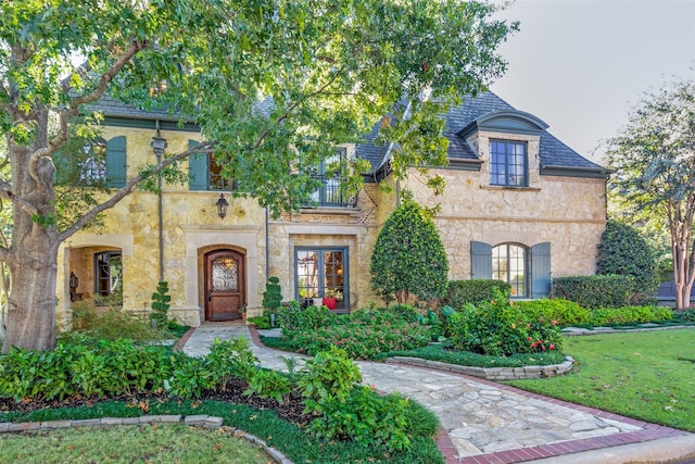 french country inspired facade featuring a balcony and a front lawn