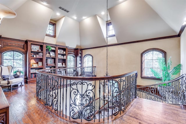 corridor with a high ceiling, hardwood / wood-style flooring, and plenty of natural light