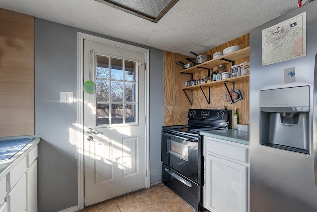 kitchen featuring a textured ceiling, stainless steel fridge, electric range, white cabinets, and light tile patterned flooring