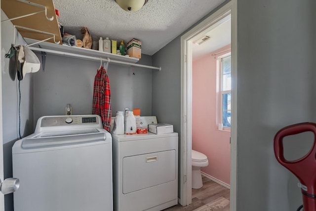 laundry room with washer and dryer, light hardwood / wood-style floors, and a textured ceiling