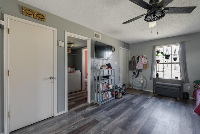 miscellaneous room with a textured ceiling, ceiling fan, dark hardwood / wood-style flooring, and washer / dryer